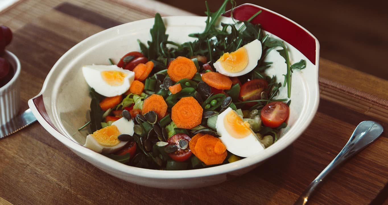 salad with carrots, tomatoes, peas, boiled eggs, and seeds